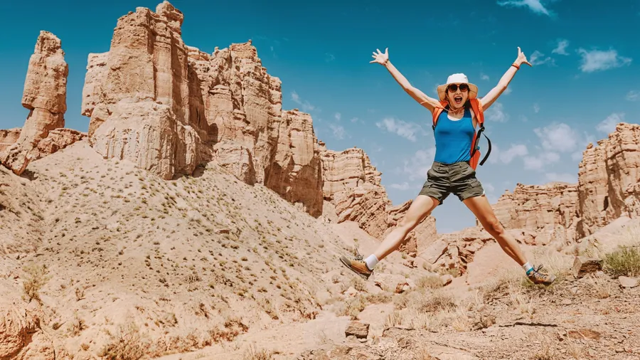 Happy hiker jumping in beautiful Charyn Canyon celebrating successful trekking travel adventure in Kazakhstan