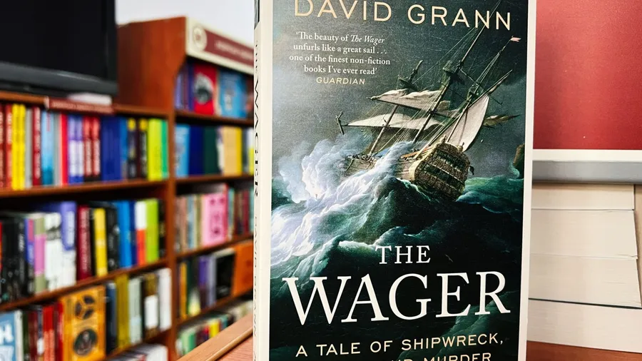 Lviv, Ukraine - February 20, 2025: The Wager by David Grann. A detailed view of a compelling historical book in a vibrant bookstore setting.