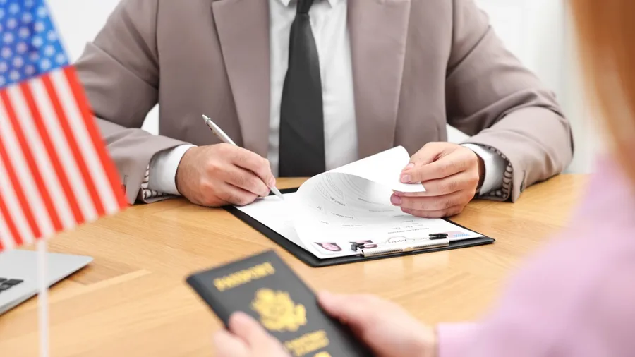 Immigration to United States of America. Embassy worker approving visa application form to woman in office, closeup