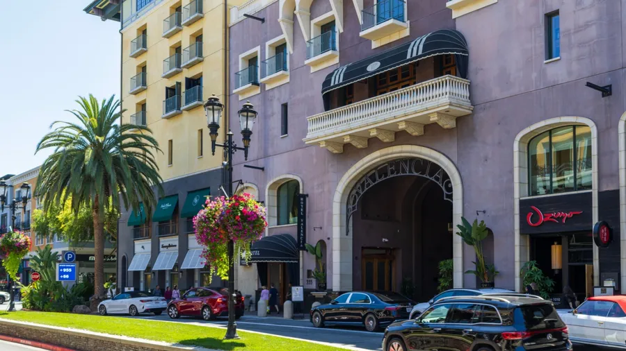 San Jose California USA - 7 15 2025: a hotel, restaurants, parked cars, palm trees, and ornate streetlights on a bright day at Santana Row Shopping Mall in San Jose California USA