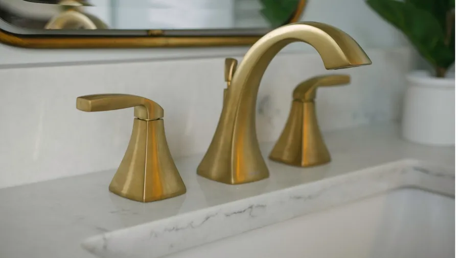 A brushed gold faucet mounted on a marble countertop.