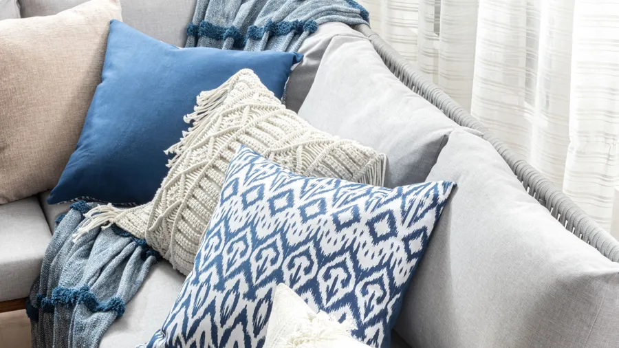 Different textured throw pillows and throw blanket on a cozy sofa.