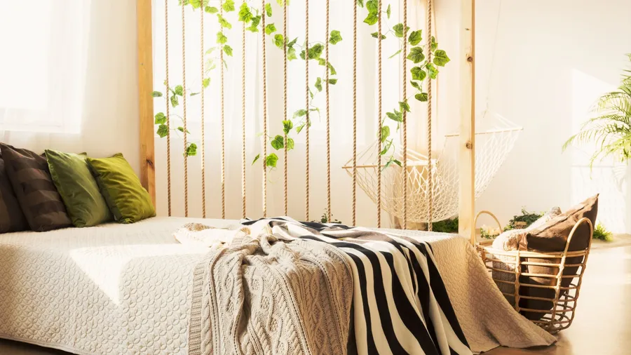 A cozy minimalist bedroom with a bed, layered throws, a rope-and-vine DIY backdrop, and soft natural lighting creating a warm, serene atmosphere.