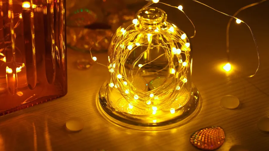 A glass jar with LED fairy lights on a table.
