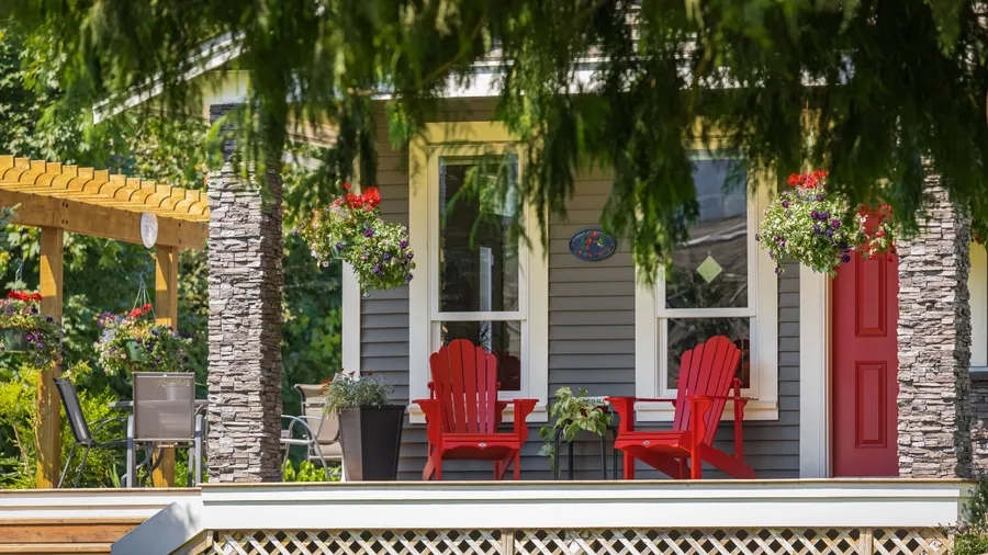 A beautiful front porch with red Adirondack chairs, a cozy small dining area, and hanging planters.