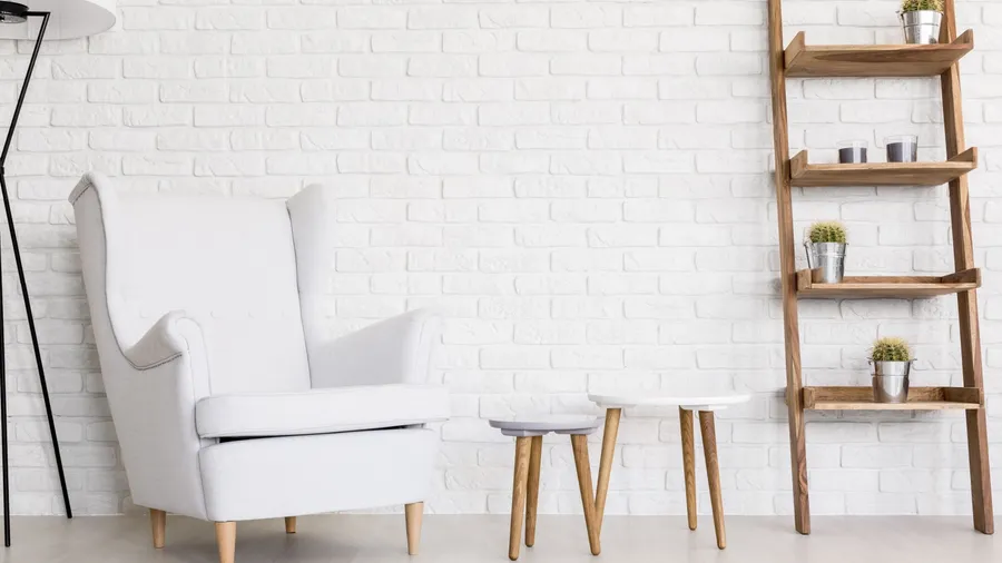 A wooden ladder shelf with small potted plants, armchair, and nested coffee table.
