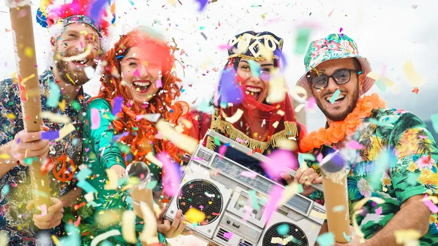 People celebrating graduation party while listening to music on a speaker with confetti flying all around them.
