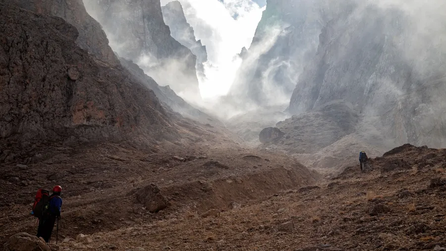 majestic and mysterious view to big mountain canyon in fog and somewhere climbers silhouettes from a far