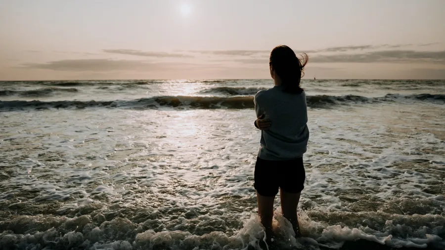 A girl stands and looks at the sunset at the sea