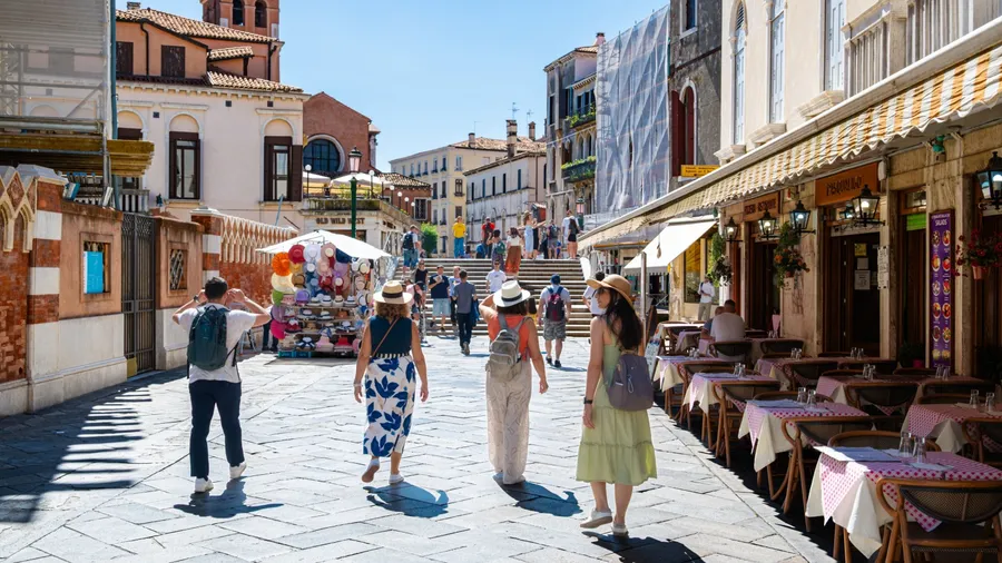 Venice, Italy. August 1, 2025. People walking through the streets on a sunny day with many tourists.