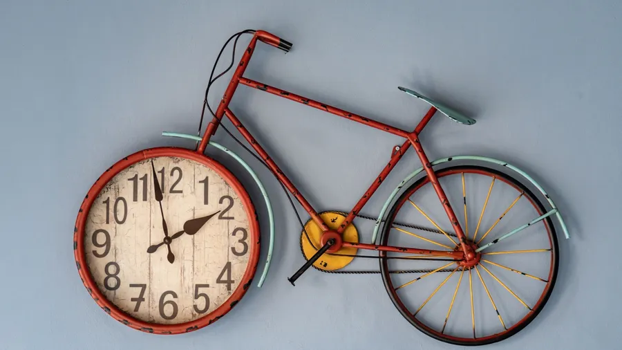 A vintage bicycle clock hanging on a blue wall.