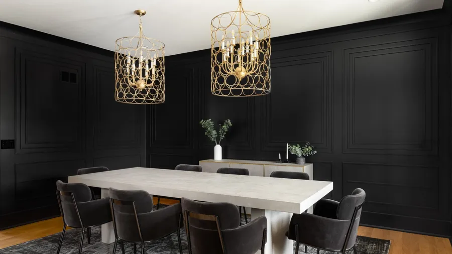 A dining room interior with black walls, console table, and gold chandeliers hanging from the white ceiling.