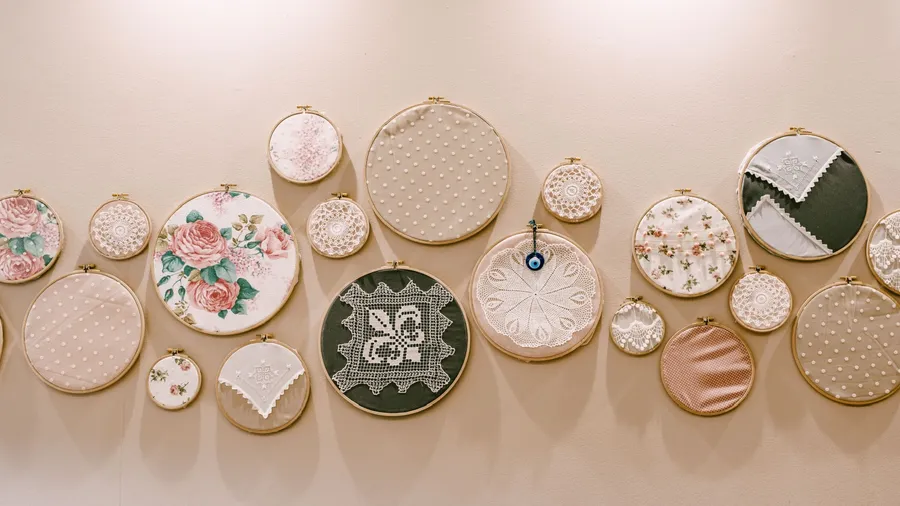 A group of round embroidery frames with pretty flowers and patterns are hung on a light-colored wall for decoration.