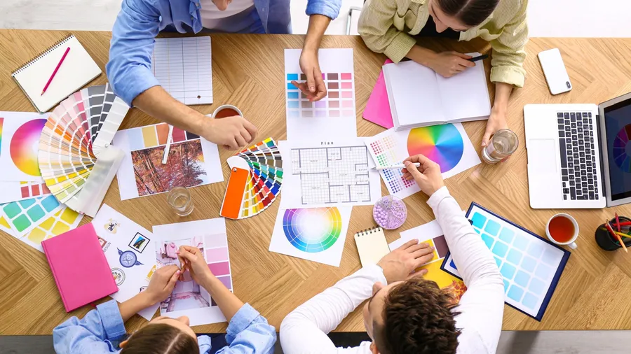 People sitting around a wooden table and discussing about colors.