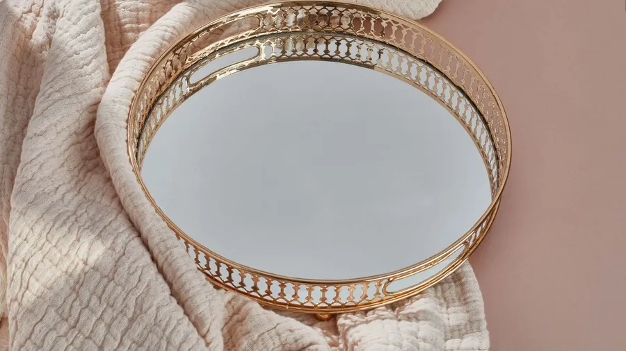 A decorative golden tray on a soft blanket, reflecting light in a stylish setting.