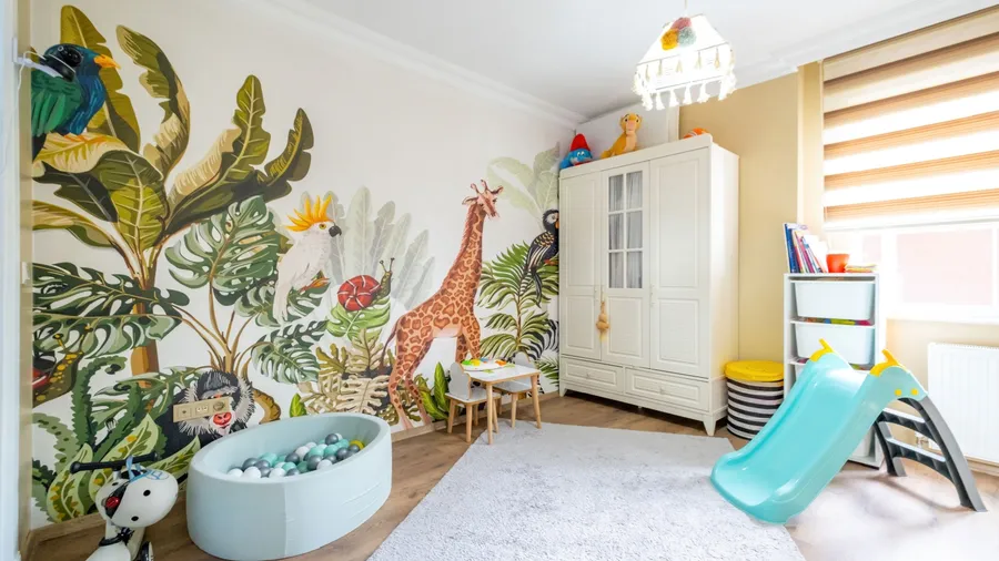 A playful children's room with jungle-themed wall art and a ball pit.