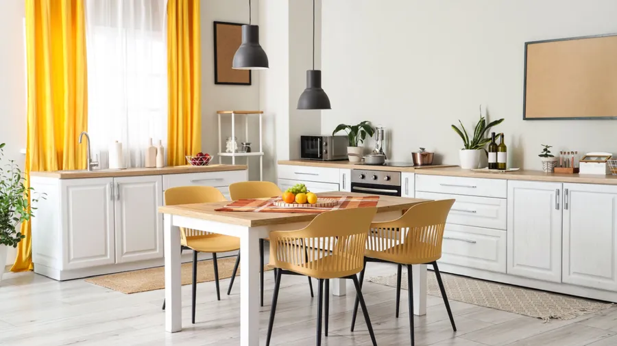 Interior of modern kitchen with white counters, dining table, yellow curtains, chairs and lamp