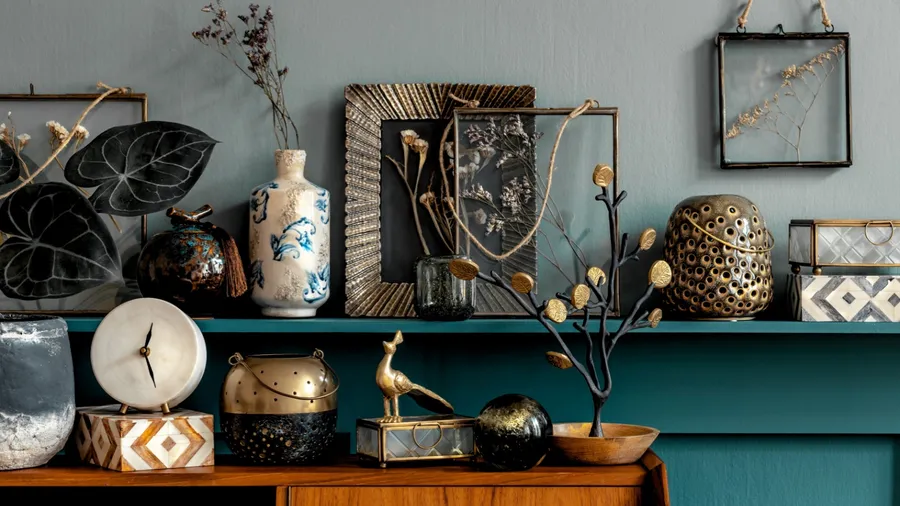 Decorated shelf with various vases and art pieces against a teal wall.