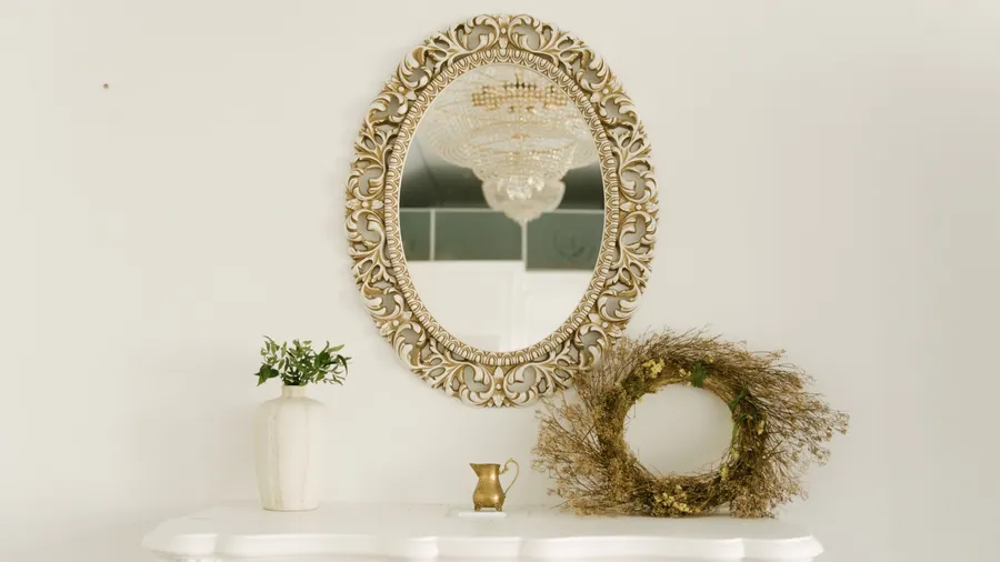 An ornate frame oval mirror hanging above a fireplace in a living room.