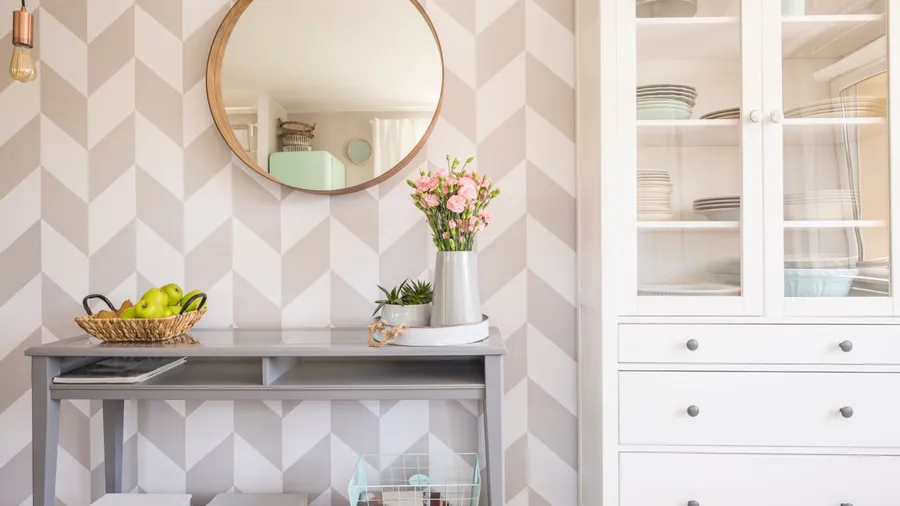 Elegant entryway with a textured wall, a circular mirror, and a flower arrangement on a tray.