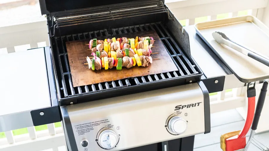 Meat and vegetable skewers on a grill.