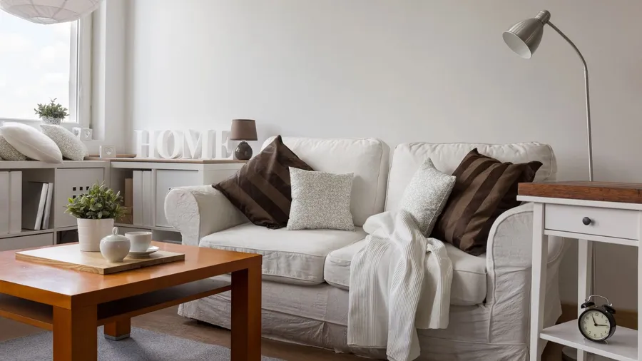 A cozy living room with a white couch, decorative pillows, and a wooden coffee table.