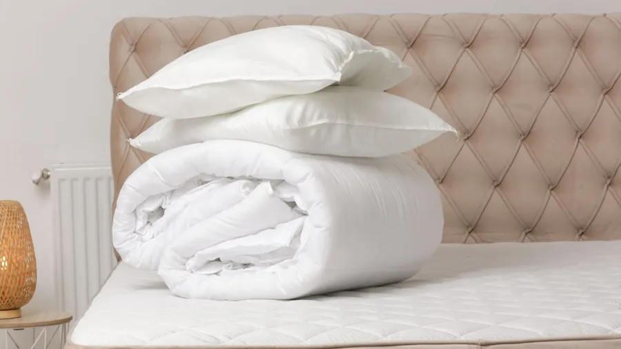 White colored folded duvet and pillows placed on a mattress
