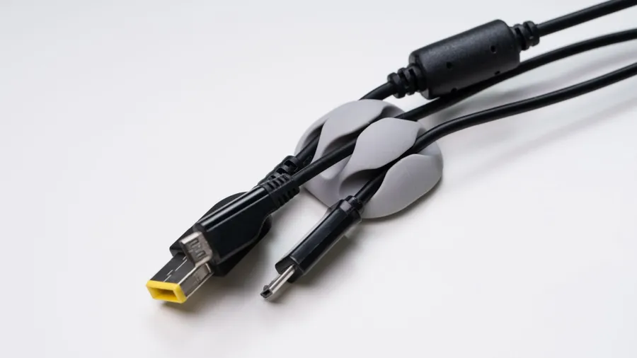 A cable holder with charging cables on a white table.