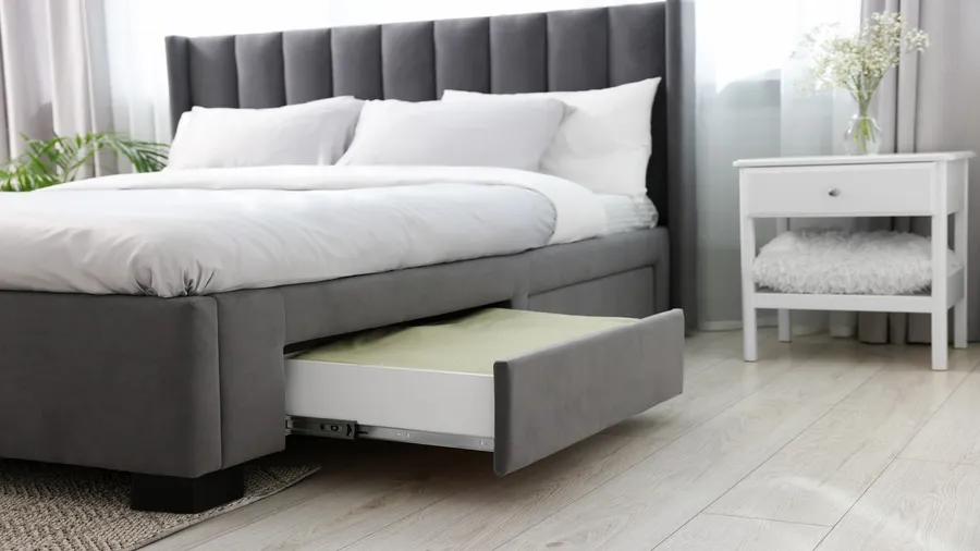 A bedroom interior with a bed with under-bed drawers for storage.
