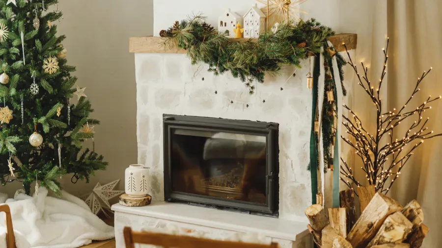 A beautiful fireplace decorated with leafy garland and wooden houses on the mantel.