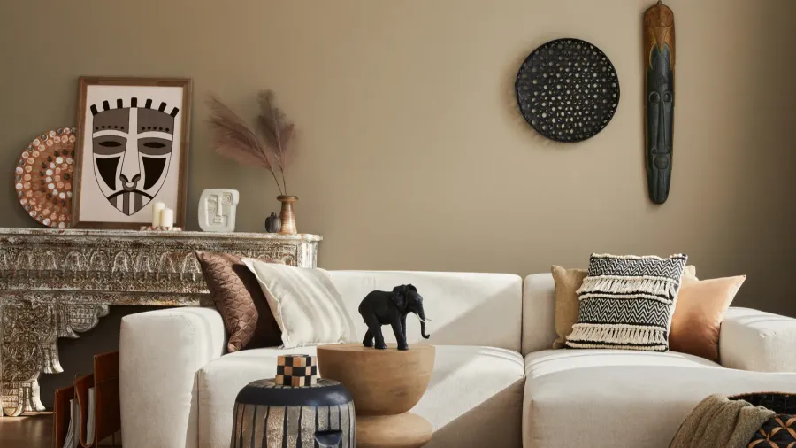 A stylish living room interior with modular sofa, coffee table, and ethnic framed artwork and decor accents.