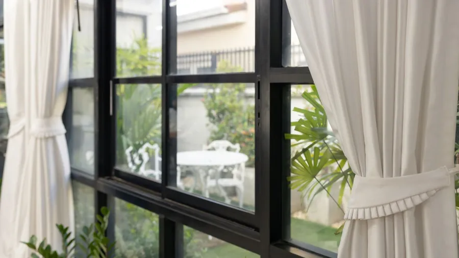 Bright room with large windows, white curtains, and a small outdoor patio.