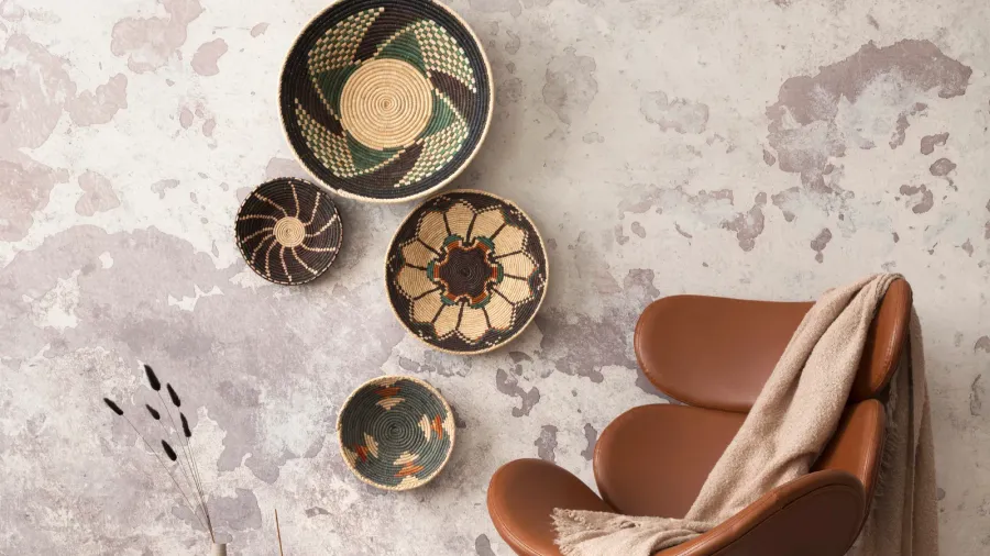The stylish ethnic composition at living room interior with design brown armchair, colorful baskets, and elegant personal accessories. Grey concrete wall. Cozy apartment. Home decor.