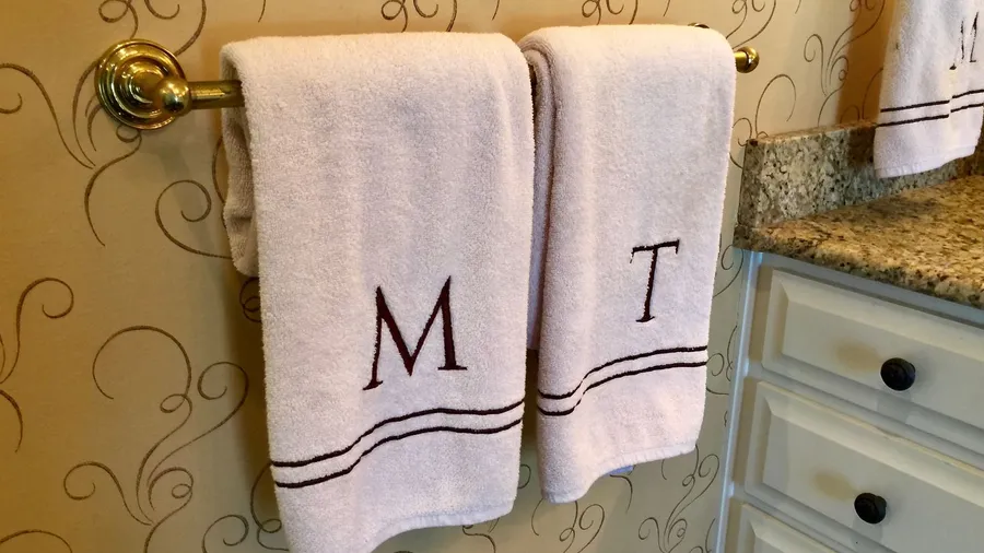 Towels with monogrammed letters M and T hanging on a rod.