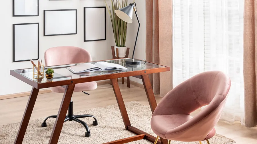 A home office interior with desk, pastel pink chairs, rug, and layered sheer curtains on the window.
