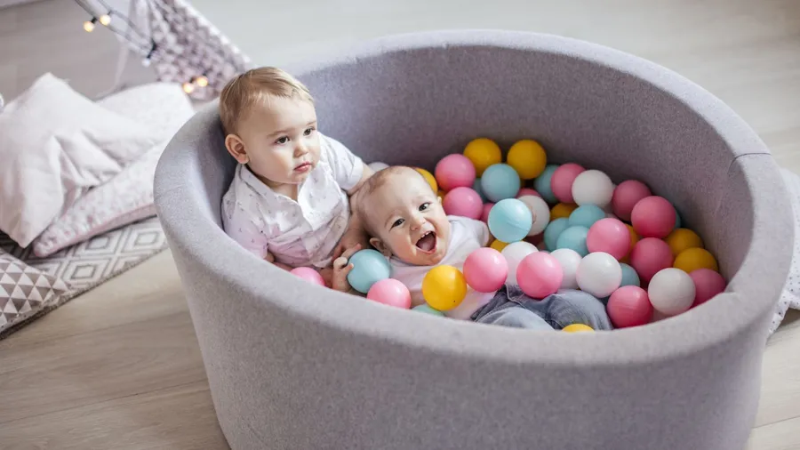 Babies enjoying in a dry pool filled with colorful balls.
