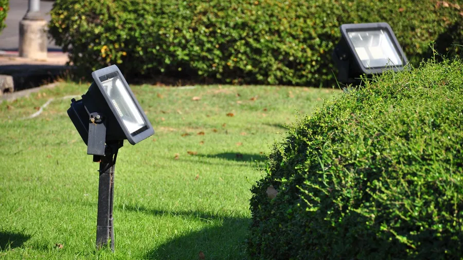 LED floodlights in a garden surrounded by bushes.