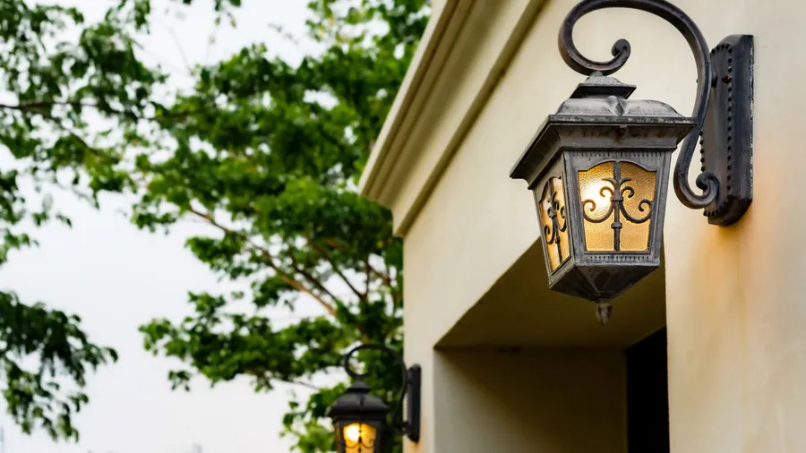 A dark metal wall sconce mounted on a light beige wall.