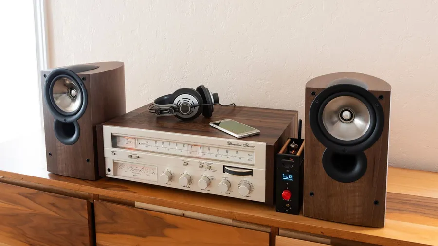 A vintage stereo receiver with speakers on a wooden shelf.