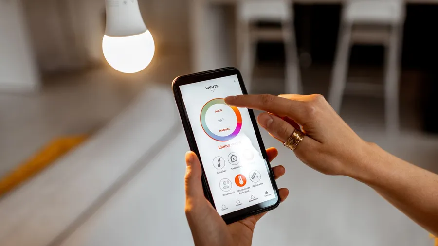 A woman using her smartphone to control smart LED light bulb.