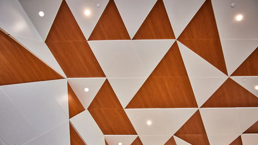 Ceiling with a modern geometric design, featuring wood and white panels with built-in lights.