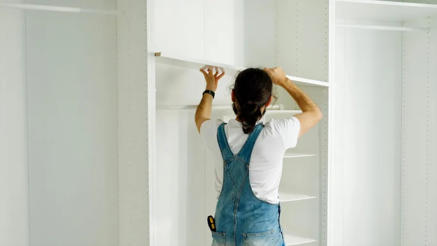A man installing adjustable shelves in a closet.