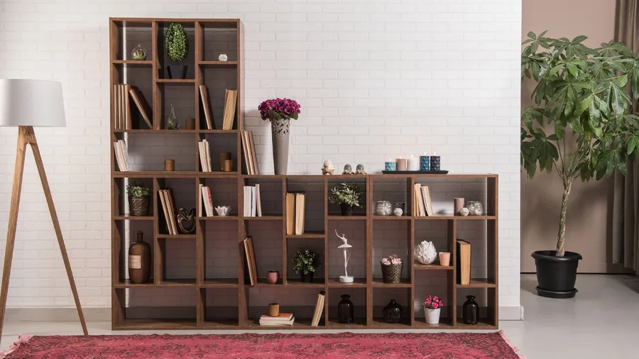 A living room with floor lamp, rug, plant, and a wooden open shelf with books, plants, candles, and decor accents.