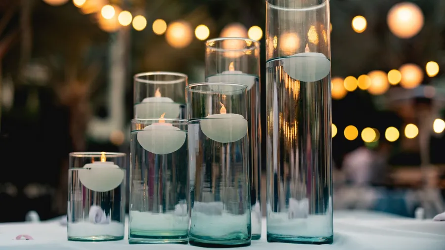 Floating candles in clear jars on a white surface.
