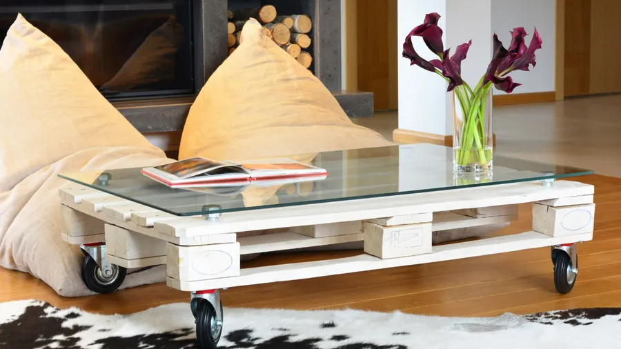 A living room interior with wooden pallet coffee table, rug, and floor cushions.