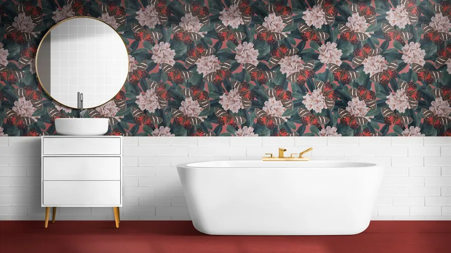 A bathroom interior with a bathtub, white vanity table, round wall mirror, and floral wallpaper on the wall.