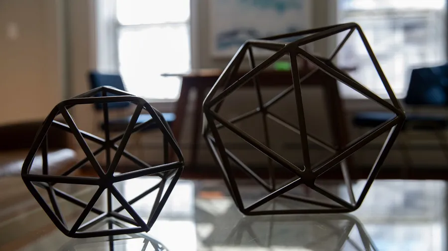 Black metallic geometric wire sculptures on a table.