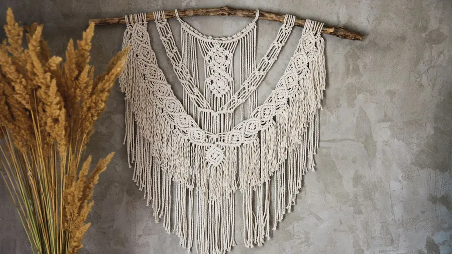 A boho macrame wall hanging on a gray wall.