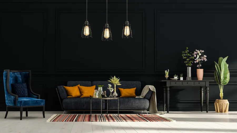 A living room interior with charcoal black sofa with cushions, coffee table, velvet armchair, black console table with decor elements, and metallic black statement lights.