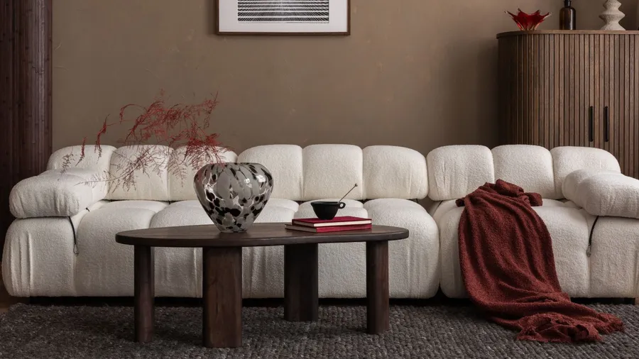 A stylish living room with a white sofa, wooden coffee table, and decorative items.